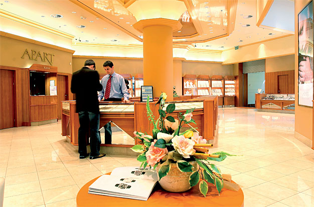 Zaakcentowanie jasnym światłem gabloty i rozproszone ciepłe światło w części sprzedażowej tworzą aurę elitarności